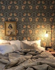 a large bed with two lamps on either side and a painting above the headboard