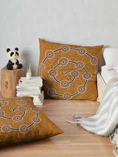 two decorative pillows sitting on top of a wooden floor next to a stack of books