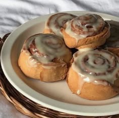 several cinnamon rolls on a white plate in a wicker basket