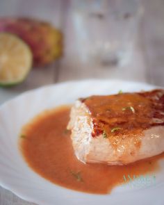 a piece of fish on a white plate with sauce