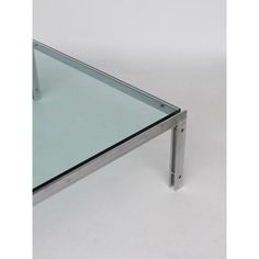 a glass table with metal legs on a white surface and no one is in the photo