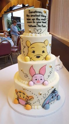 a three tiered cake with winnie the pooh characters on it