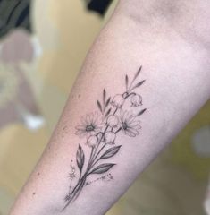 a black and white flower tattoo on the left arm, with flowers growing out of it