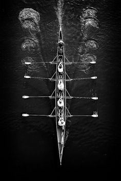 an aerial view of a rowing boat with eight rowers in the water, taken from above