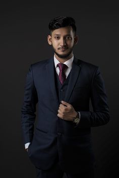 a man in a suit and tie posing for the camera with his hands on his chest