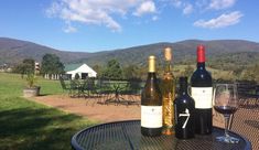 three bottles of wine sitting on top of a table next to two glasses of wine