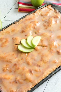 a casserole dish with apples and caramel sauce on top, next to an apple slice