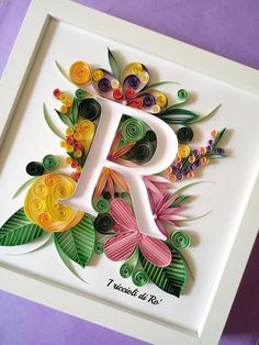 the letter person made out of paper with flowers and leaves on it is displayed in a white frame