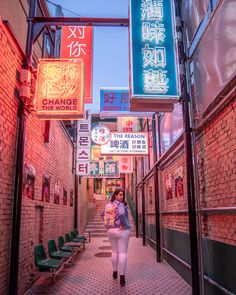 a woman walking down an alley way with neon signs