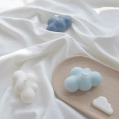 three soaps sitting on top of a wooden tray next to a white sheet covered bed