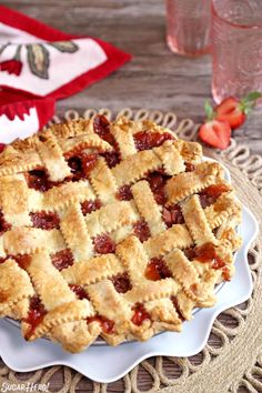 a close up of a pie on a plate with strawberries in the back ground