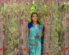 a woman standing in front of a wall covered with beads