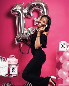 a woman in a black dress is talking on the phone and balloons are around her