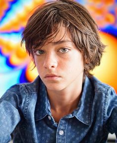 a close up of a person wearing a denim shirt and looking at the camera with an artistic background