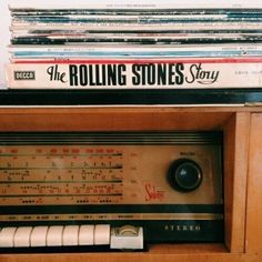 an old radio sitting on top of a wooden shelf filled with books and vinyl records