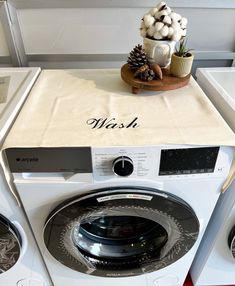 a washer sitting on top of a dryer next to a potted plant