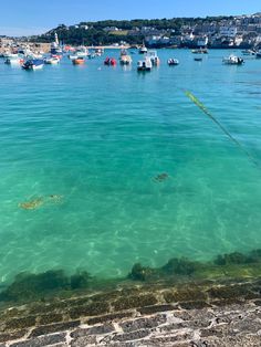 there are many small boats in the water at this beach area with clear blue water