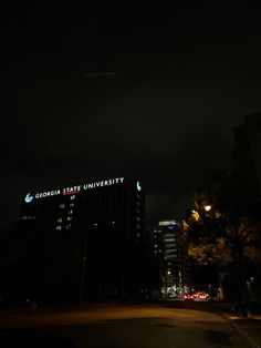 an airplane is flying in the night sky over a building with lights on it's side