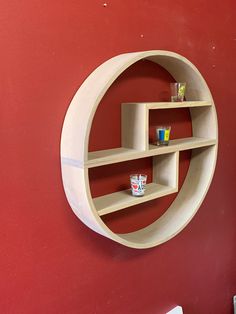 a red wall with a circular shelf on the side that has cups and glasses in it