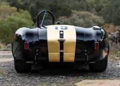 a black and yellow sports car sitting on top of a gravel road