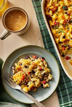 a casserole dish on a plate next to a cup of coffee and a glass of orange juice