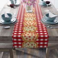 the table is set with plates, cups and vases on it's long red checkered runner