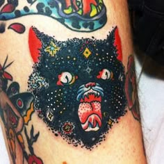 a tattoo with an image of a black cat on it's leg and some other tattoos