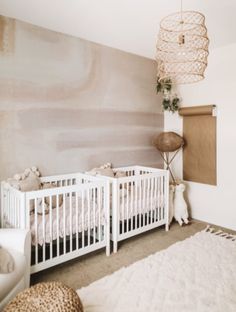 a baby's room with two cribs and a rug on the floor