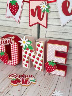 the letters are made out of wood and have strawberries on them, along with bunting