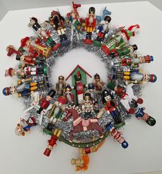 a christmas wreath made out of toy figurines and tinsels on a white surface