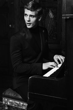 a man in a tuxedo sitting at a piano with his hands on the keys