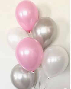 a bunch of balloons that are in the shape of flowers on a white wall with pink and silver accents