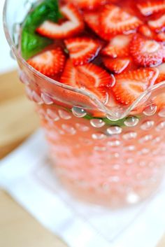 a glass bowl filled with sliced strawberries on top of a table