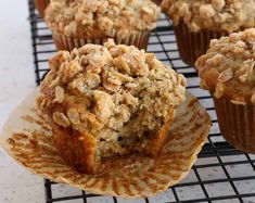 several muffins on a cooling rack with one cut in half to show the crumbs