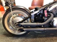 a close up of a motorcycle on the ground with a leather chair in the background