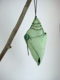 a green ornament hanging from a tree branch