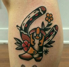 a tattoo on the back of a woman's leg with an image of a boot and flowers