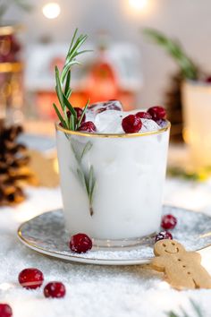 a glass filled with ice and cranberries on top of a white table cloth