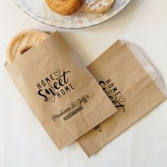 two donuts sitting on top of a white plate next to brown paper bag bags