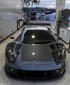 a black sports car parked in front of a gas station with its hood open and lights on