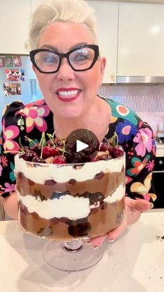 a woman in glasses is holding a cake