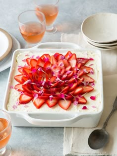 there is a bowl of food with strawberries on it and two glasses next to it