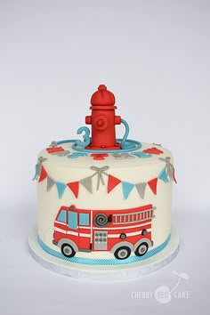 a birthday cake with a fire truck on top and bunting around the edges,