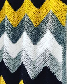 a crocheted blanket with yellow, gray and white stripes