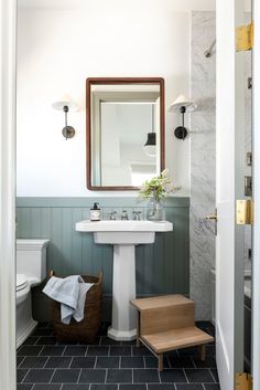 a white sink sitting under a mirror in a bathroom next to a wooden step stool