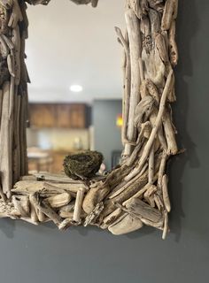 a mirror made out of driftwood with a bird nest on the top of it