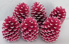 several red and white pine cones sitting on top of a table next to each other