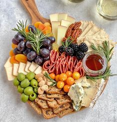 an assortment of cheeses, meats and fruit on a platter