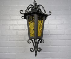 an old fashioned street light hanging on a white brick wall with gold coins in it