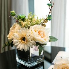 a vase filled with flowers sitting on top of a table next to a box of tissues